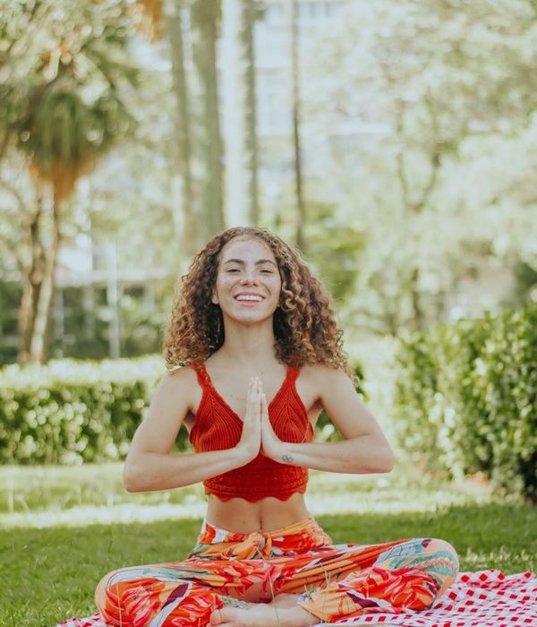 Smiling woman stretching gently on a yoga mat in a bright space.