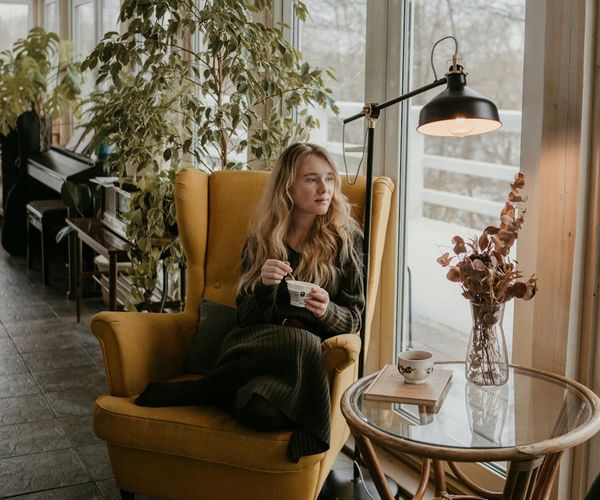 Woman sipping tea and looking out a window peacefully.
